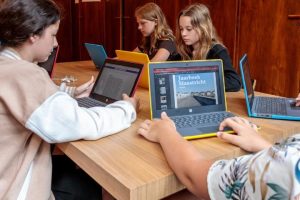 Kinderen achter een laptop kijken naar een online versie van het Jaarboek Maastricht.